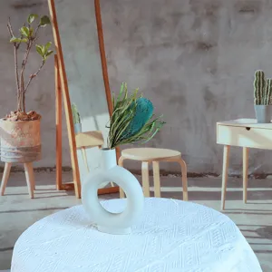 Detail view of natural dried banksia flowers in a modern white ceramic ring vase setup.