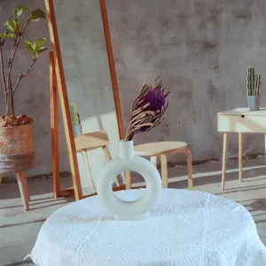 Minimalist ceramic donut vase with natural dried flower arrangement for interior decor.