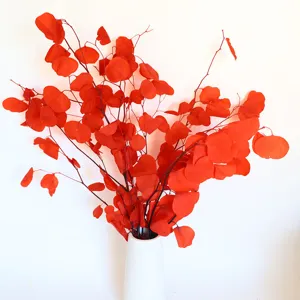 Detailed close-up of vibrant red dried eucalyptus leaves arrangement in a white ceramic vase.