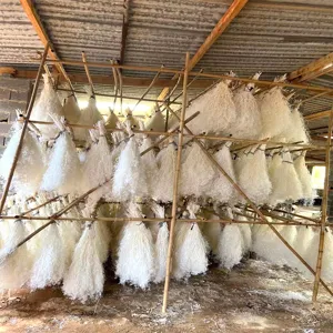 Detail view of natural dried baby's breath flowers hanging on bamboo racks for drying process.