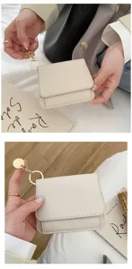 Detailaufnahme des minimalistischen kurzen Portemonnaies in Beige mit goldenem Ring.