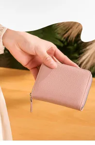 Close-up detail shot of a pink textured leather zipper wallet held nicely in hand.
