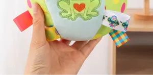Detalle de pelota de juguete para perros de peluche, juguete interactivo verde con rana bordada.