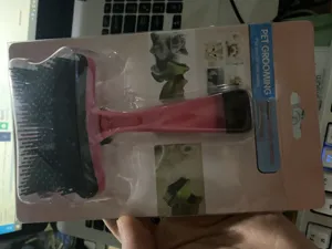 Pet grooming brush for cats and dogs, pink handle and black bristles in blister package.
