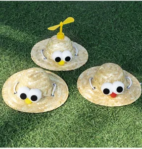 Close-up detail of cute pet straw hats with funny big eyes and a yellow bamboo propeller.