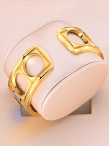 Gold cuff watch detail shot, featuring a unique geometric cutout design and metallic finish.