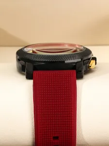Men's sports quartz watch with black textured bezel, gold accents and red silicone strap.