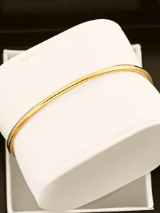 Elegant gold-colored metal bangle detail showcasing polished surface and sleek curve design.
