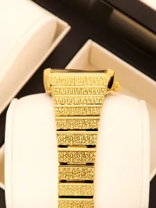 Gros plan détaillé d'un bracelet de montre en or texturé de luxe, finition élégante.
