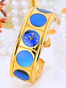 Gold tone bangle watch detail featuring striking blue round dial and decorative accents.