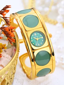 Gold cuff bracelet watch detail, green round stone inlay, elegant vintage women watch close up