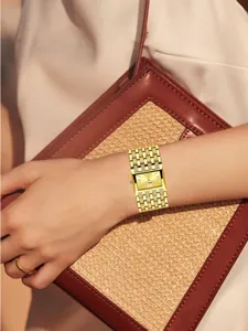 Primer plano detallado de un lujoso reloj de pulsera para mujer dorado con esfera cuadrada y correa.