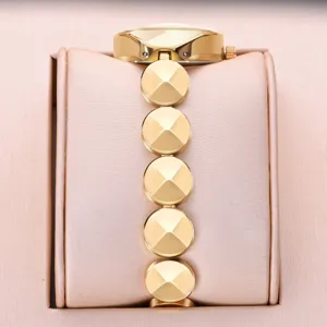 Gold tone women watch with unique pyramid stud links and elegant presentation pillow display.
