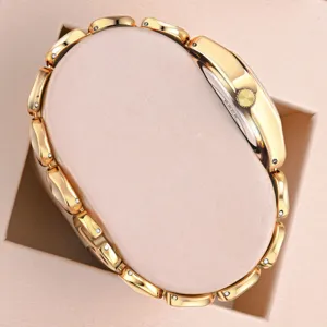 Detailed view of luxury gold-plated women's chain watch displayed on elegant beige pillow.