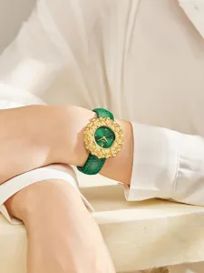 Luxury women's wristwatch featuring an emerald green dial, gold floral bezel, and green leather strap.