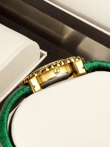 Luxury women's quartz wristwatch featuring a gold case and a stylish green leather strap.
