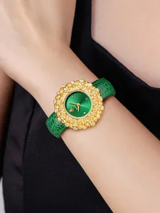 Women luxury emerald dial watch with gold floral crystal bezel and green leather strap detail.