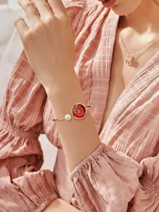 Elegante orologio rigido da donna in oro con quadrante rosso e perla delicata.