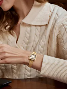 Detailed shot of women's vintage square gold watch with rhinestone bezel and mesh strap.