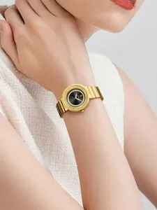 Gros plan détaillé d'une montre quartz dorée pour femme avec lunette diamant et cadran noir.