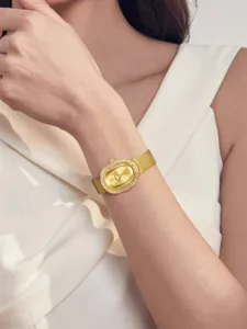 Vista detallada de un elegante reloj de mujer ovalado dorado con strass y pulsera malla.