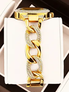 Vista detallada de reloj de cuarzo mujer lujo en oro con pedrería brillante y correa de cadena.