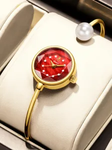 Vista dettagliata del lussuoso orologio rigido dorato con quadrante sfaccettato rosso e perla.