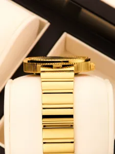 Gros plan détaillé d'une montre quartz dorée luxueuse avec une lunette sertie de diamants étincelants.