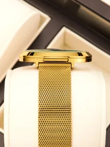 Detailed view of luxury gold quartz watch with mesh strap displayed neatly on elegant pillow.