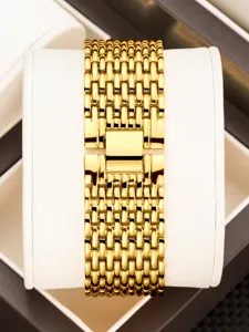 Close-up of elegant gold watch bracelet strap with polished links and secure clasp detail.