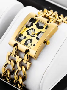 Nahaufnahme einer goldenen Damen-Quarzuhr mit Leoparden-Glitter-Zifferblatt und Doppelkettenarmband.