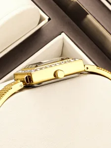 Close-up detail of women luxury square gold watch case, showing crystal bezel and crown.
