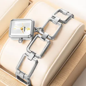 Primer plano detalle del reloj de pulsera cuadrado para mujer con brazalete calado y colgante.