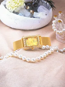 Close-up of a gold rectangular quartz watch with sparkling rhinestones, mesh strap, and dial.