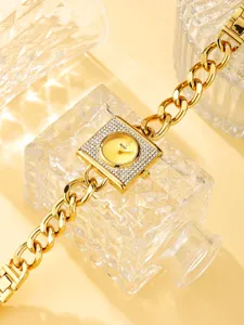 Primer plano de reloj de cuarzo dorado para mujer con esfera cuadrada y correa de cadena.
