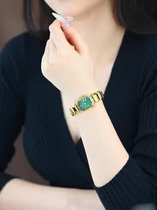 Gros plan détail de montre quartz élégante pour femmes avec cadran vert et bracelet or.