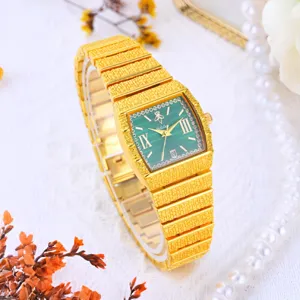 Detail de montre quartz carree doree, cadran vert avec chiffres romains et bracelet metallique.