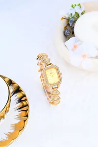 Luxury gold women watch with sparkling rhinestone square dial and unique fan bracelet design.