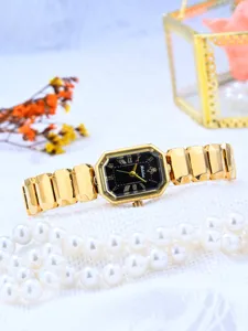 Montre à quartz rectangulaire dorée, bracelet en métal élégant et cadran noir chic en gros plan.