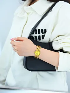 Primo piano dettagliato dell'elegante orologio con bracciale a catena dorata al polso della modella.