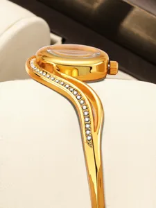 Detail view of the luxury gold bangle watch featuring a curved crystal-inlaid bracelet band.