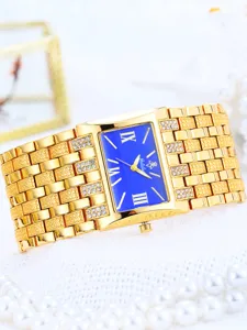 Detalle de primer plano de reloj de mujer dorado de lujo con esfera cuadrada y pedrería.