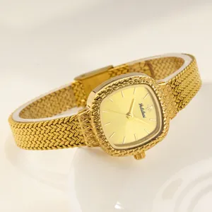 Goldfarbenes quadratisches Zifferblatt mit Struktur und filigranes Metallarmband im Detail.