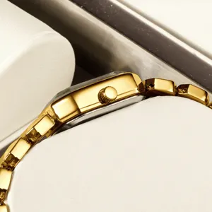 Montre quartz carrée dorée pour femme, élégant garde-temps métallique sur coussin blanc.