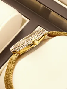 Close-up side view of luxury gold women watch with crystal bezel and mesh strap detail.