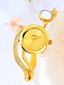 Close-up of a luxurious gold bangle watch with sparkling rhinestones and a chic dial detail.