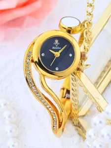 Close-up detail of luxury gold bangle watch with black dial and sparkling crystal rhinestones.