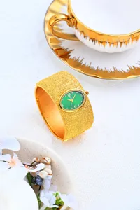 Reloj de pulsera ancho dorado de lujo con esfera ovalada verde y cuarzo elegante.