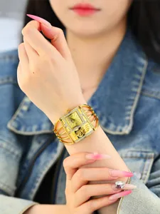Vista detallada de un reloj brazalete dorado para mujer con correa de jaula y pedrería.