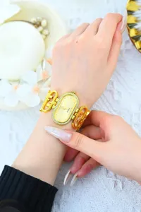 Gold oval quartz watch detail showcasing shimmering rhinestone bezel and elegant metal strap design.